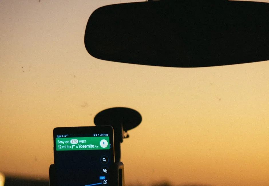 A smartphone showing GPS map navigation mounted in a car at sunset