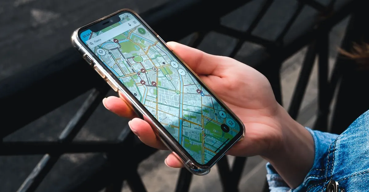 A hand holding a smartphone running a city map navigation app outdoors
